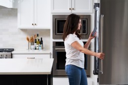 A Neli customer awaiting instructions from a technician while standing in front of her fridge.