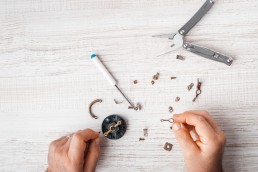 Workers assemble a mechanism with a screwdriver and pliers